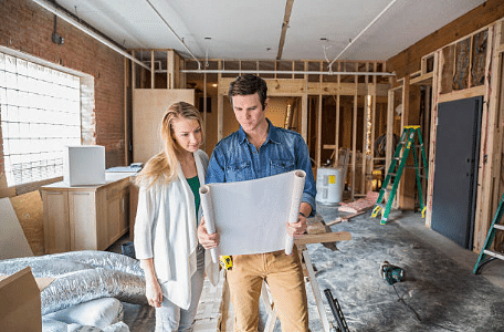 deux personnes regardant des plans dans une maison en construction